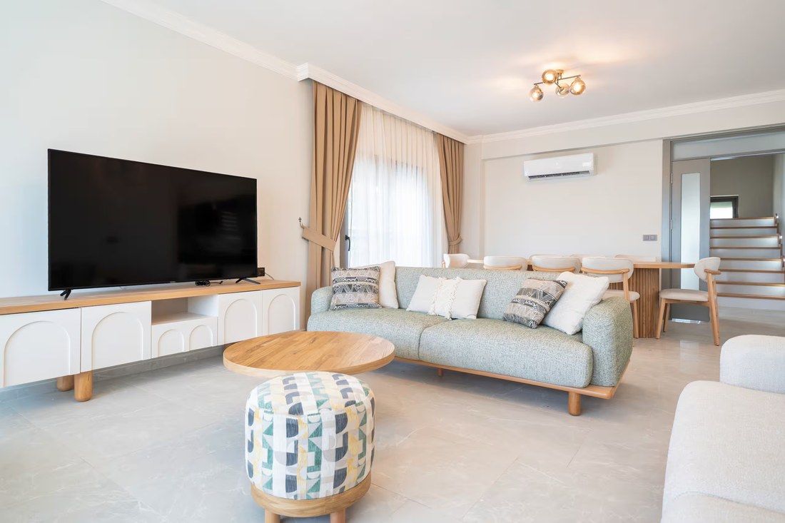 The villa living room with a pale sofa, low table and stairs to the upper floor