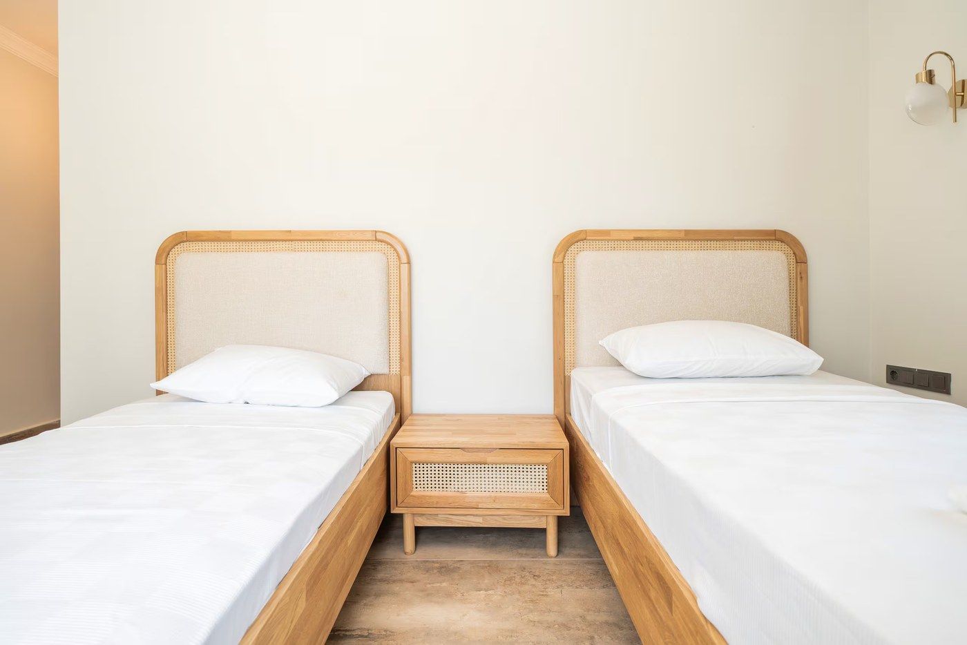 Two single beds with cane headboards either side of a shared rattan nightstand
