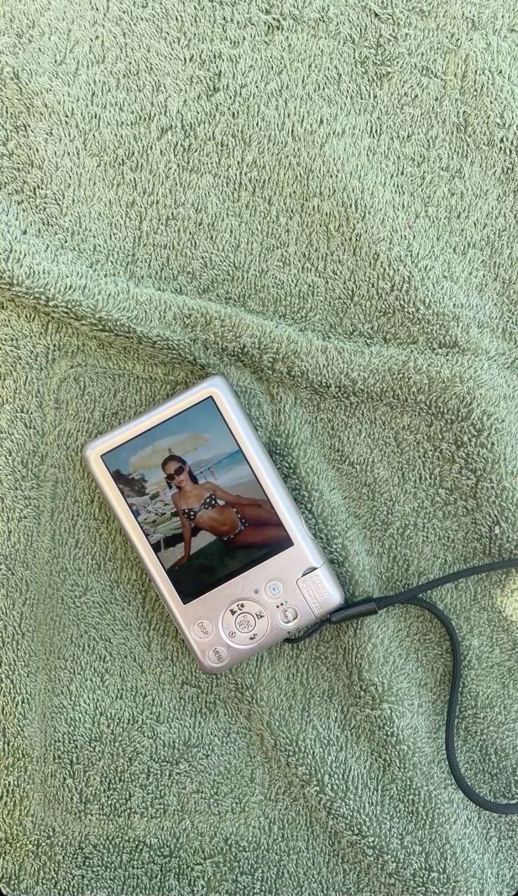 A digital camera resting on a sea-green beach towel