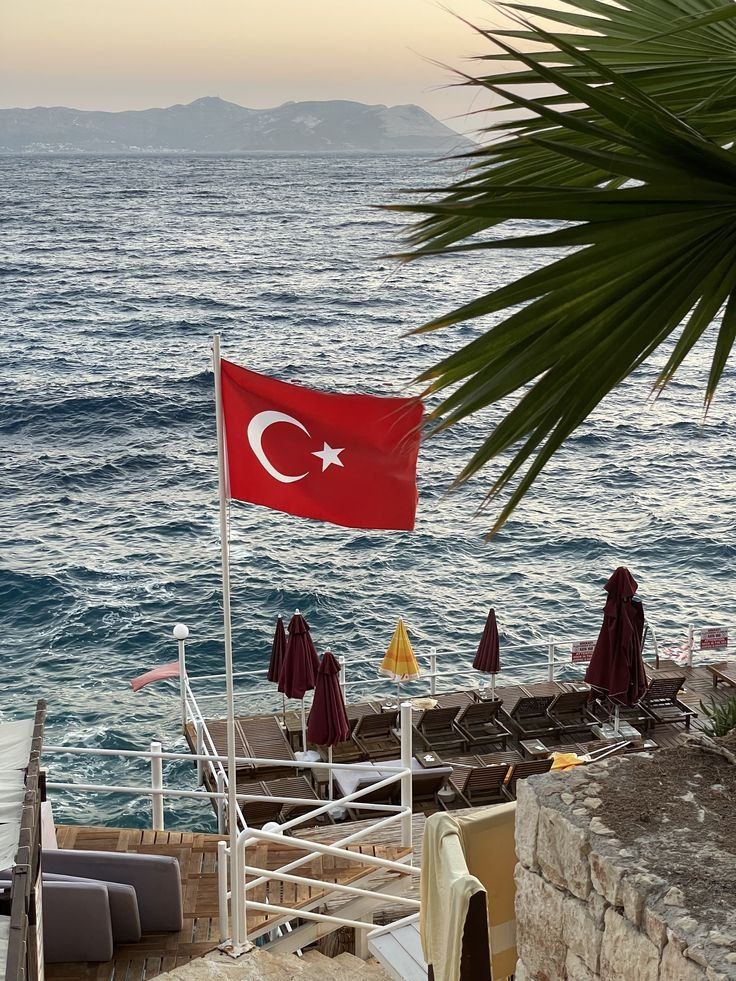 A Turkish flag flying over a beach club terrace at golden hour