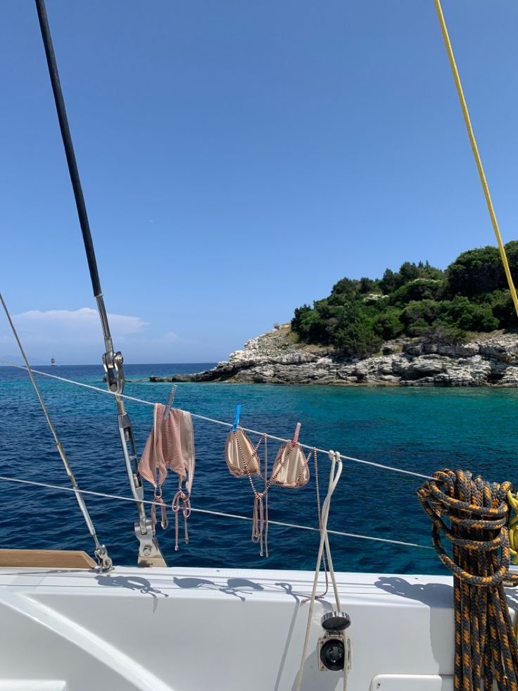 Swimsuits pegged along the rigging of a sailboat above clear water