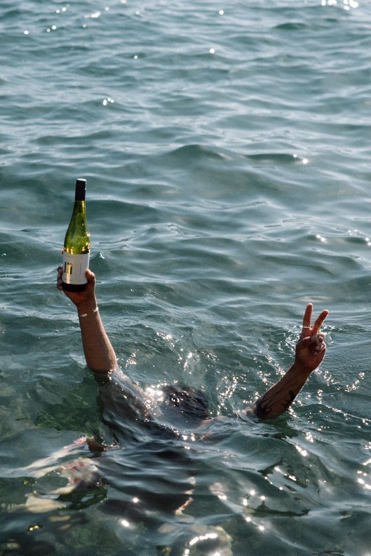 A bottle of wine and a peace sign raised out of the sea