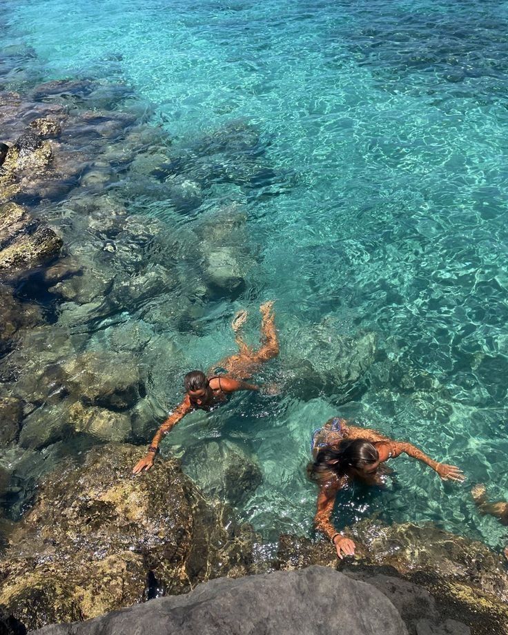 Two swimmers drifting over bright turquoise shallows