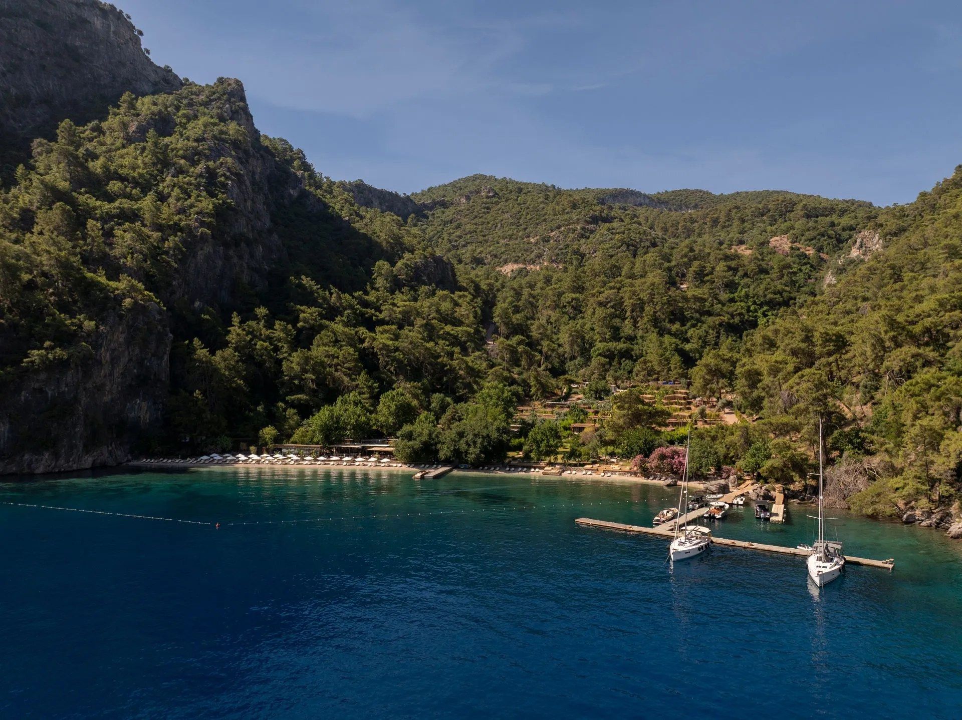 Aerial view of a sheltered turquoise cove near Fethiye with yachts moored along a jetty