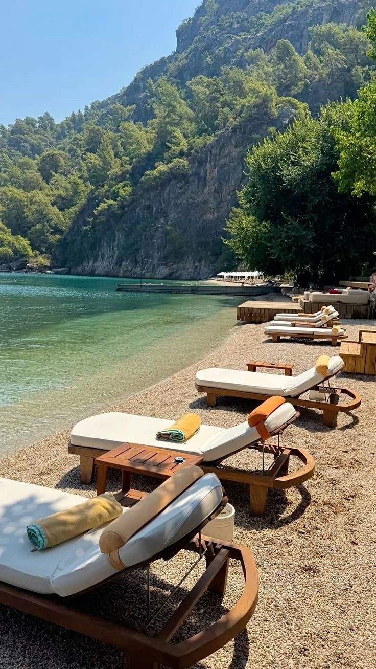 Wooden sunbeds with rolled towels on the pebble shore of a Fethiye beach club